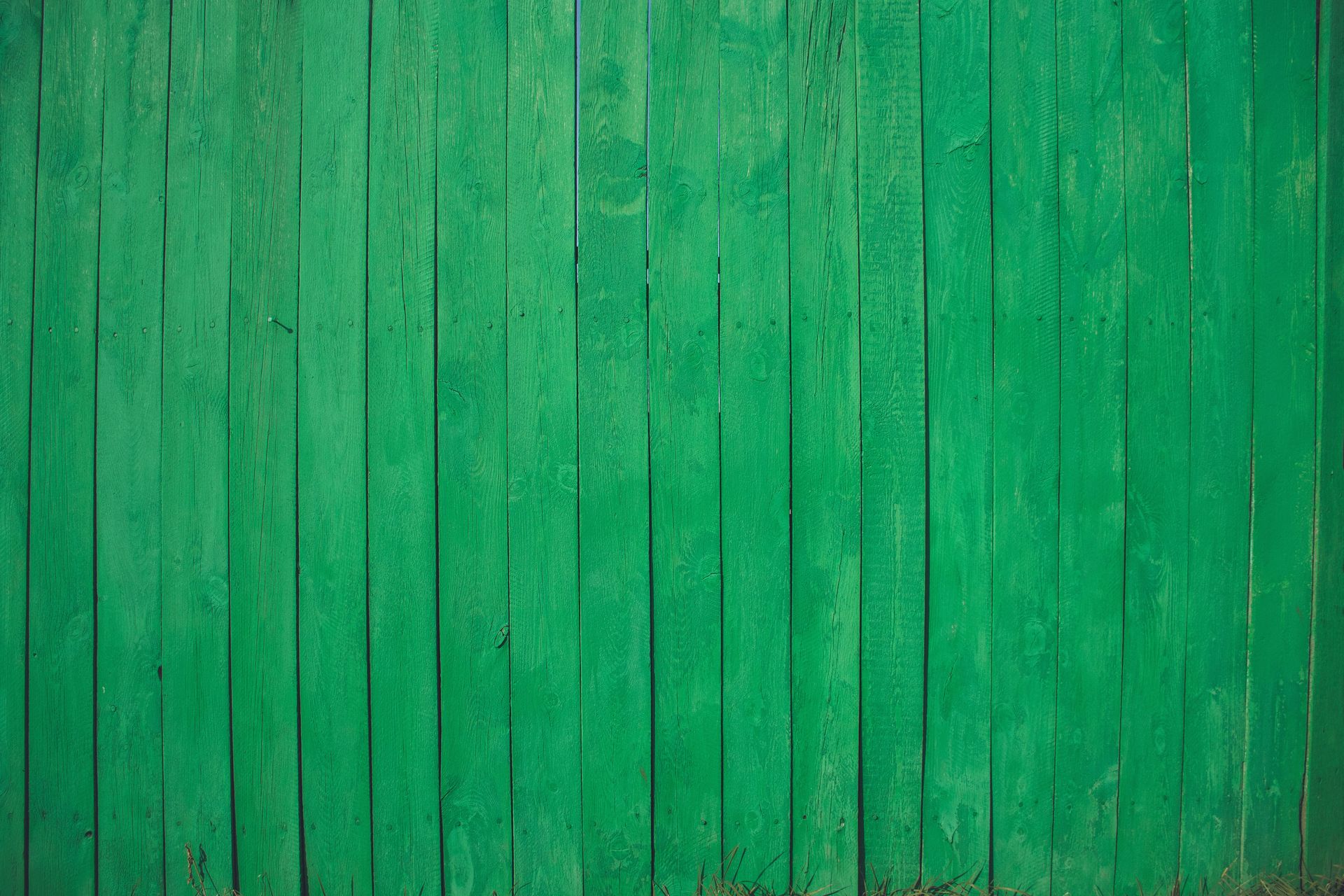 Vibrant green wooden fence texture with vertical planks for background use.